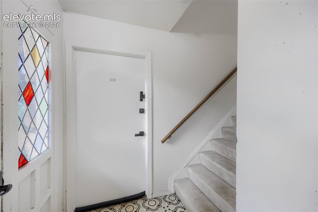 Image 24 of 28: Entryway featuring a white door, stained glass window, patterned floor tile
