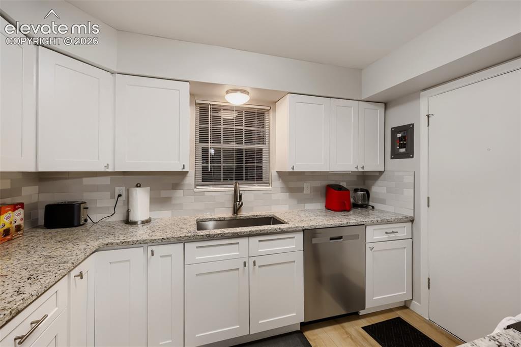 Image 4 of 28: Kitchen featuring white shaker-style cabinetry, a stainless steel sink with