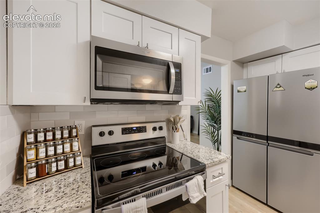 Image 5 of 28: Modern kitchen featuring white shaker cabinetry, stainless steel appliances