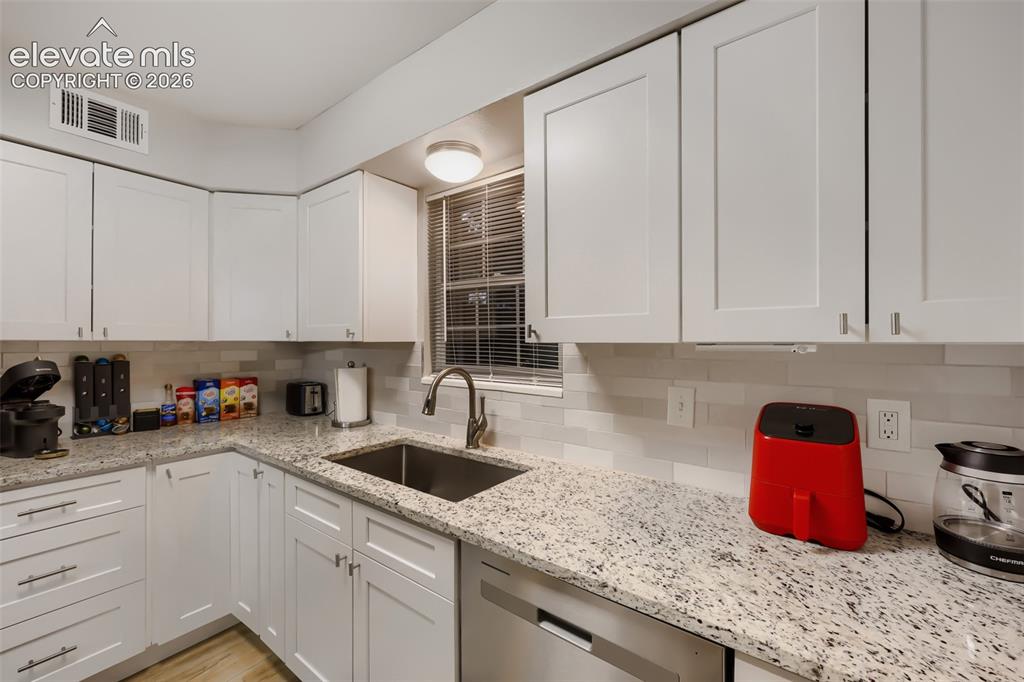 Image 6 of 28: Kitchen featuring white shaker-style cabinetry, granite countertops, and a