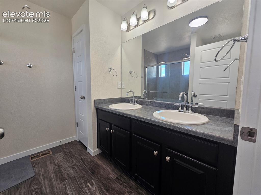Image 15 of 23: Dual vanity with dark wood-finish cabinetry, chrome fixtures, and a large m