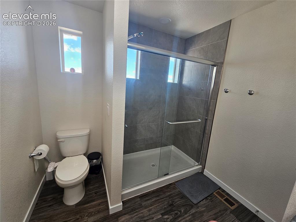 Image 16 of 23: Walk-in shower with glass enclosure, gray tile surround, and white shower p