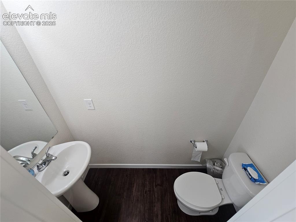Image 4 of 23: Pedestal sink with chrome faucet, dark wood-finish flooring, and white wall
