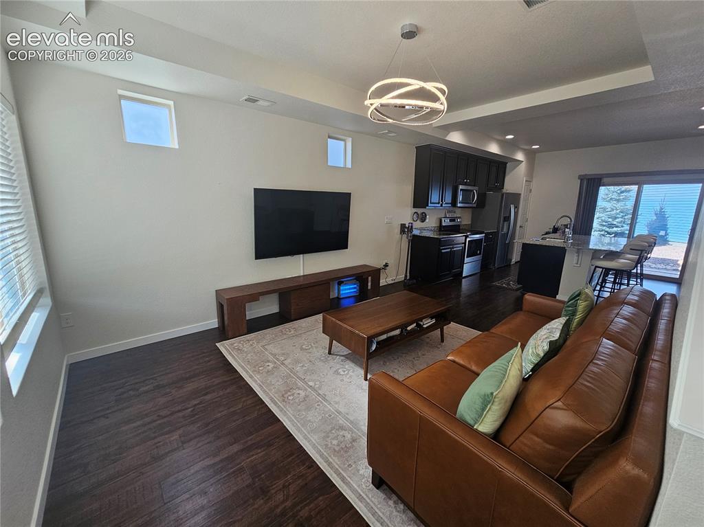 Image 5 of 23: Spacious open-concept living area showcasing dark wood-finish flooring, a l