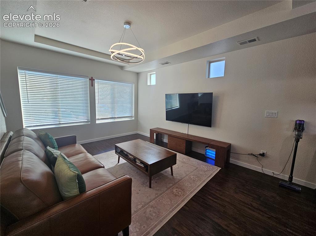 Image 6 of 23: Recessed ceiling detail with a contemporary chandelier and dark wood-finish