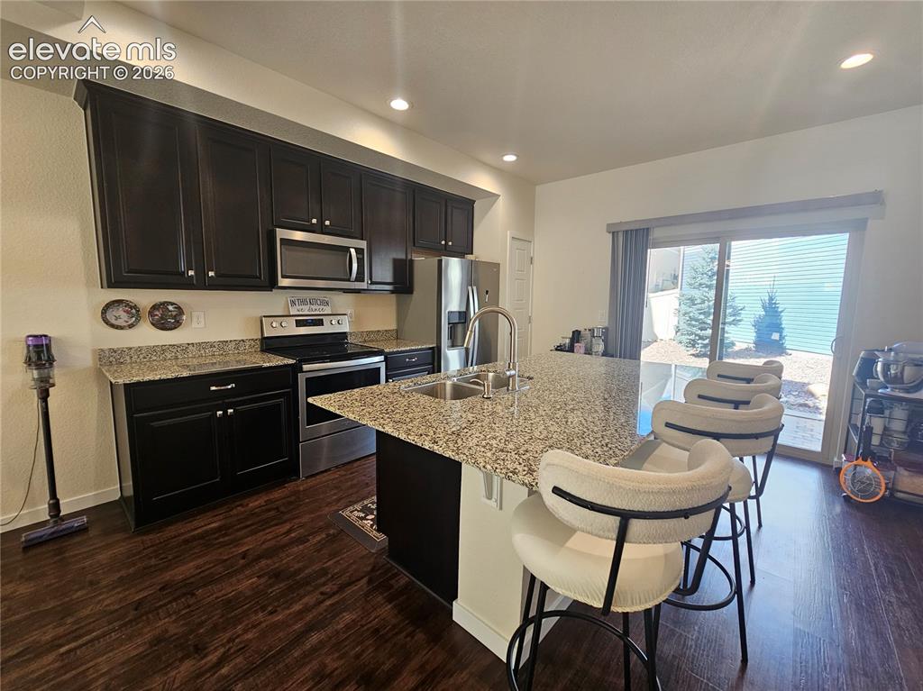 Image 7 of 23: Dark wood-finish flooring, dark cabinetry, stainless steel appliances, gran