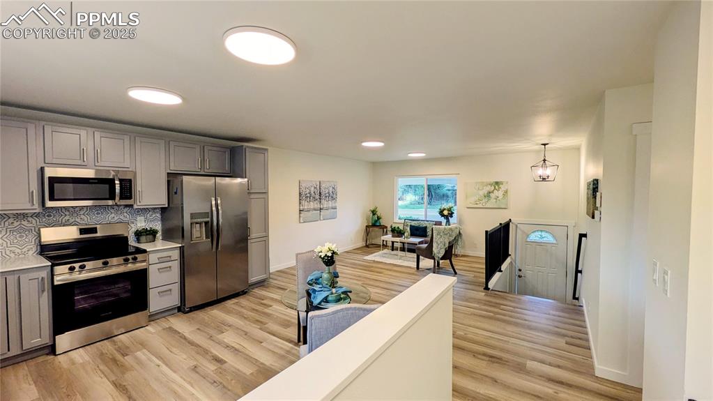 Image 10 of 39: Kitchen featuring appliances with stainless steel finishes, backsplash, gra
