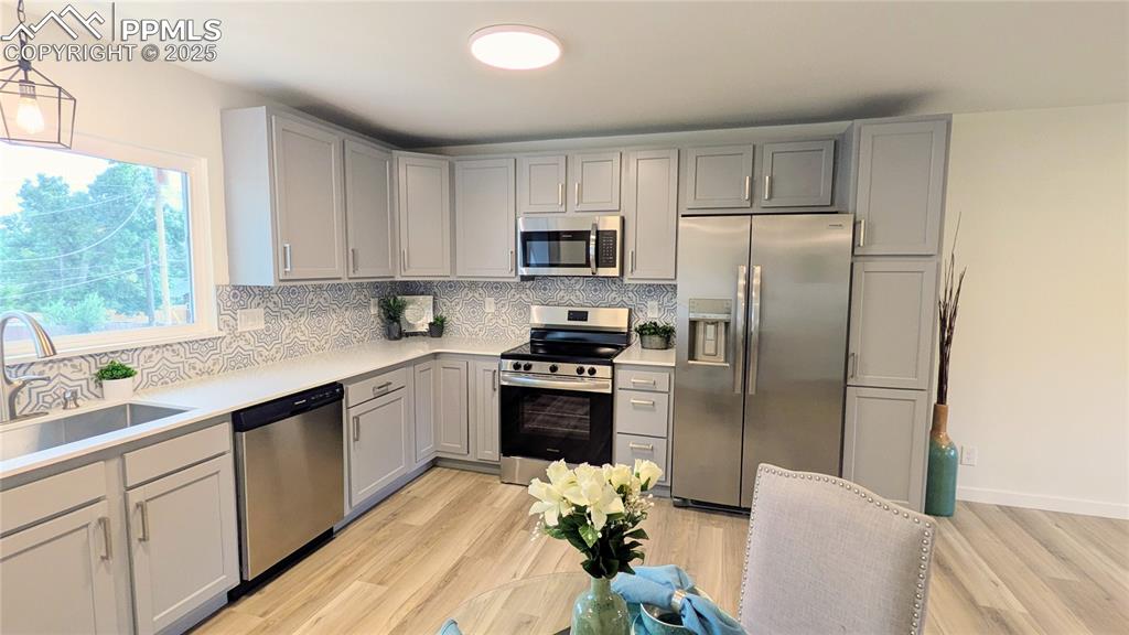 Image 11 of 39: Kitchen with stainless steel appliances, tasteful backsplash, gray cabinets