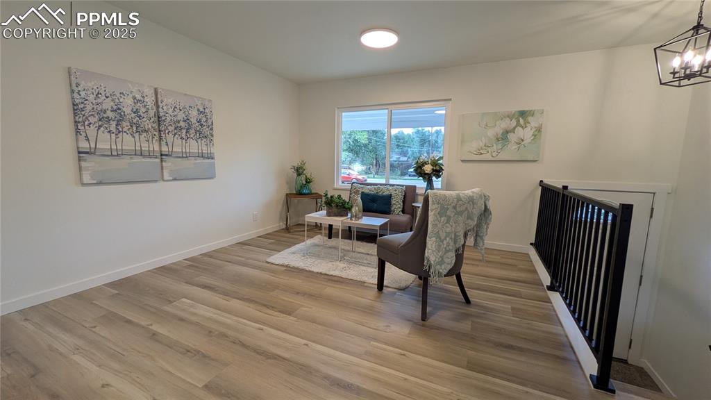 Image 12 of 39: Sitting room with light wood finished floors and a chandelier