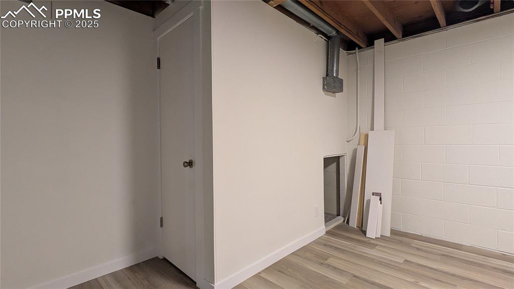 Image 28 of 39: Laundry area with light wood-style flooring and concrete block wall