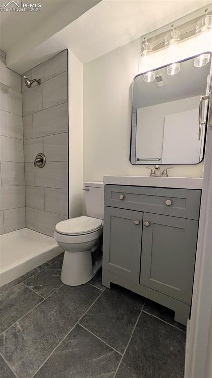 Image 31 of 39: Bathroom featuring vanity, a stall shower, and dark tile patterned flooring