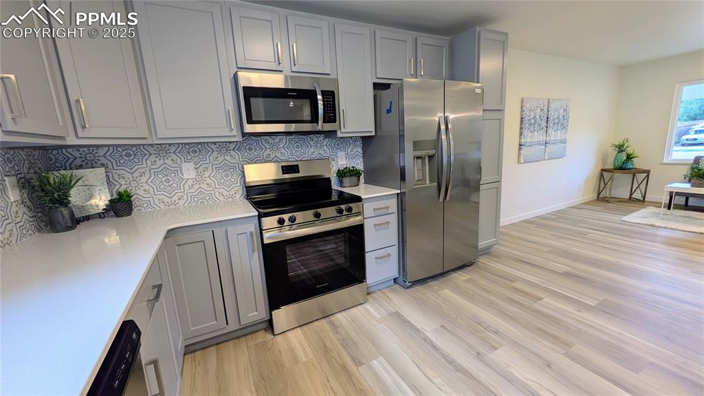 Image 37 of 39: Kitchen featuring stainless steel appliances, tasteful backsplash, gray cab