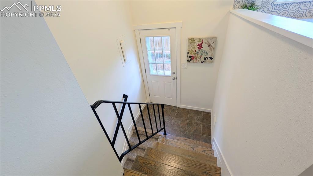 Image 38 of 39: Stairs with baseboards and stone finish floors