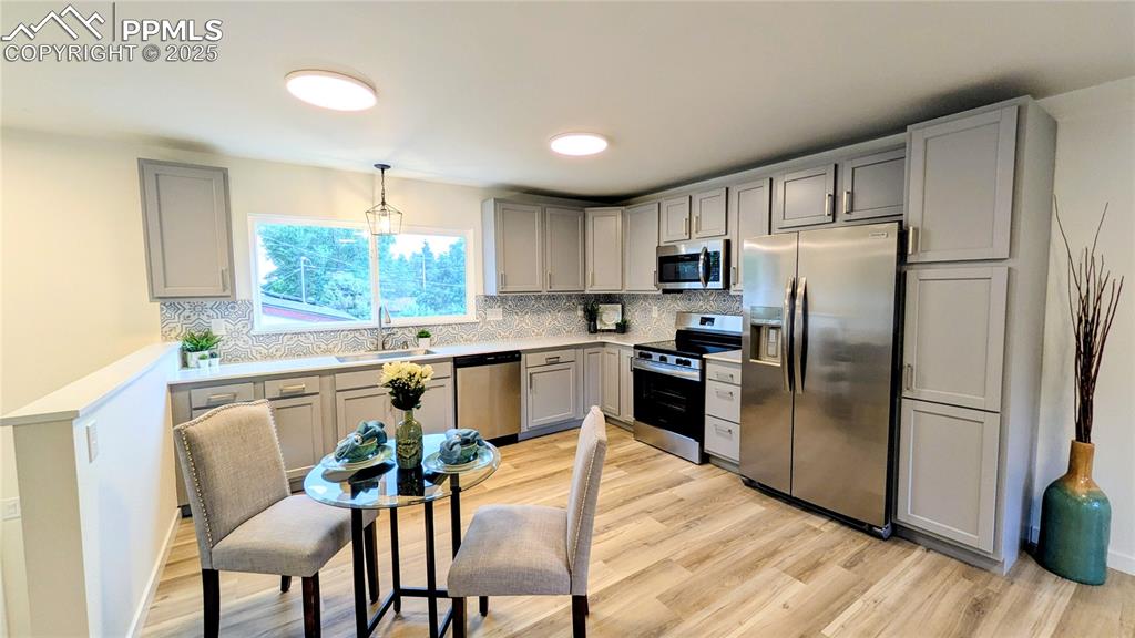 Image 9 of 39: Kitchen with gray cabinets, stainless steel appliances, decorative backspla