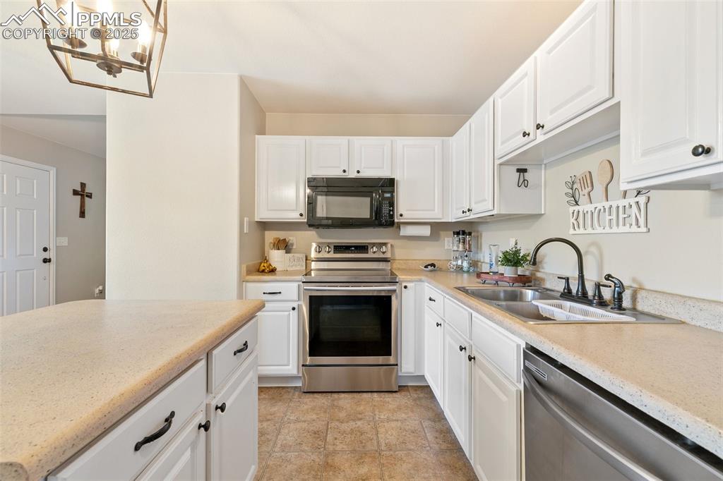 Image 12 of 27: Kitchen featuring appliances with stainless steel finishes, white cabinets,