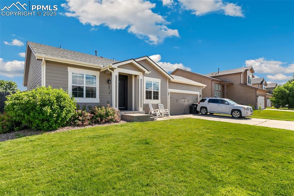 Image 2 of 27: Ranch-style home featuring a garage, driveway, a front yard, and roof with