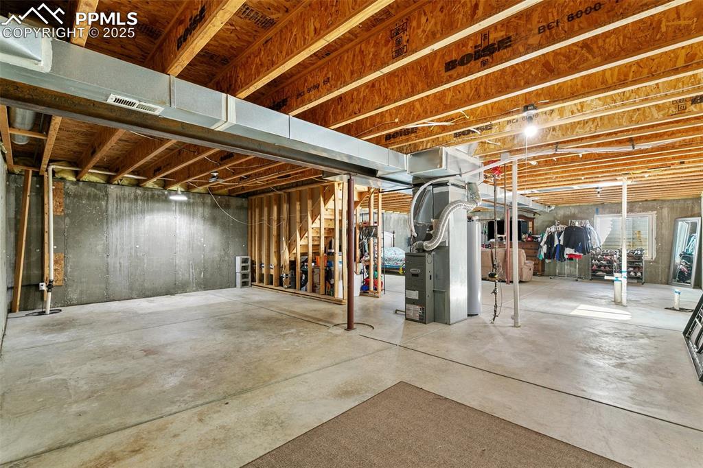 Image 25 of 27: Unfinished basement featuring stairs and water heater