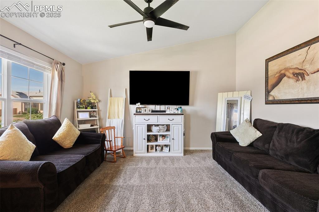 Image 4 of 27: Living room with lofted ceiling, carpet floors, and a ceiling fan