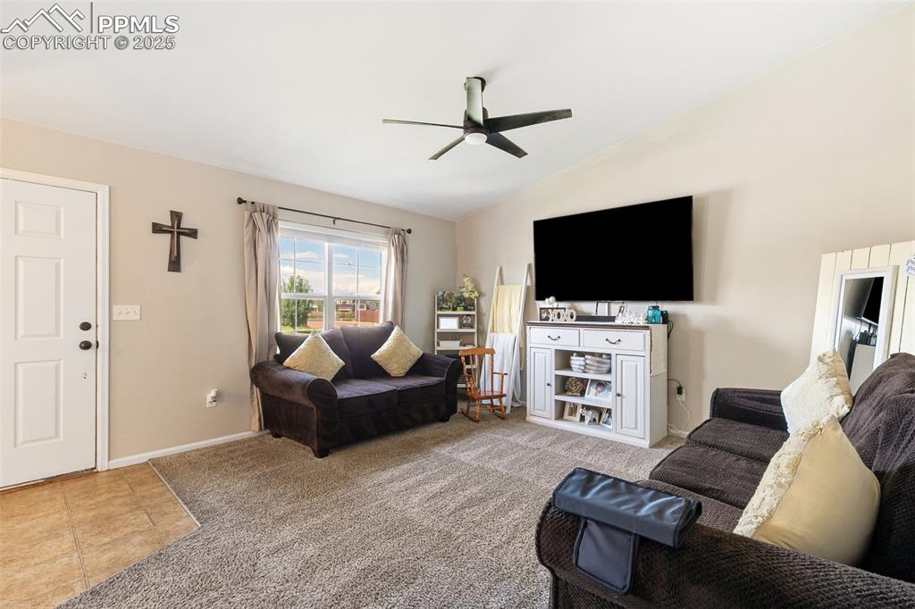 Image 5 of 27: Living room featuring a ceiling fan, lofted ceiling, and carpet