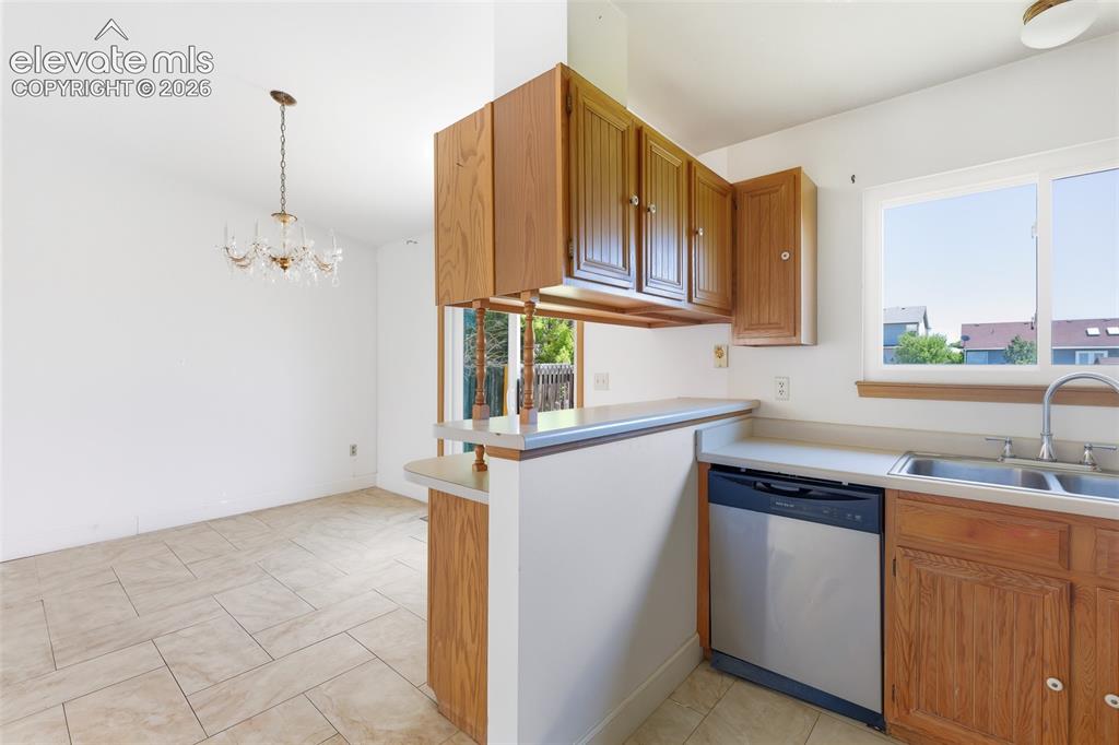 Image 10 of 29: Kitchen with wood cabinetry, stainless steel dishwasher, and dual basin sin