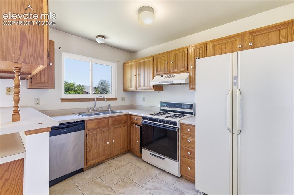 Image 11 of 29: Kitchen featuring wood cabinetry, laminate countertops, a double basin stai