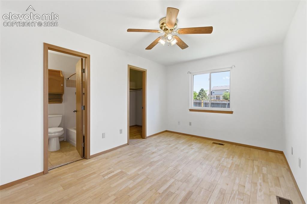 Image 12 of 29: Bright room with light wood-finish flooring, a ceiling fan with light kit, 