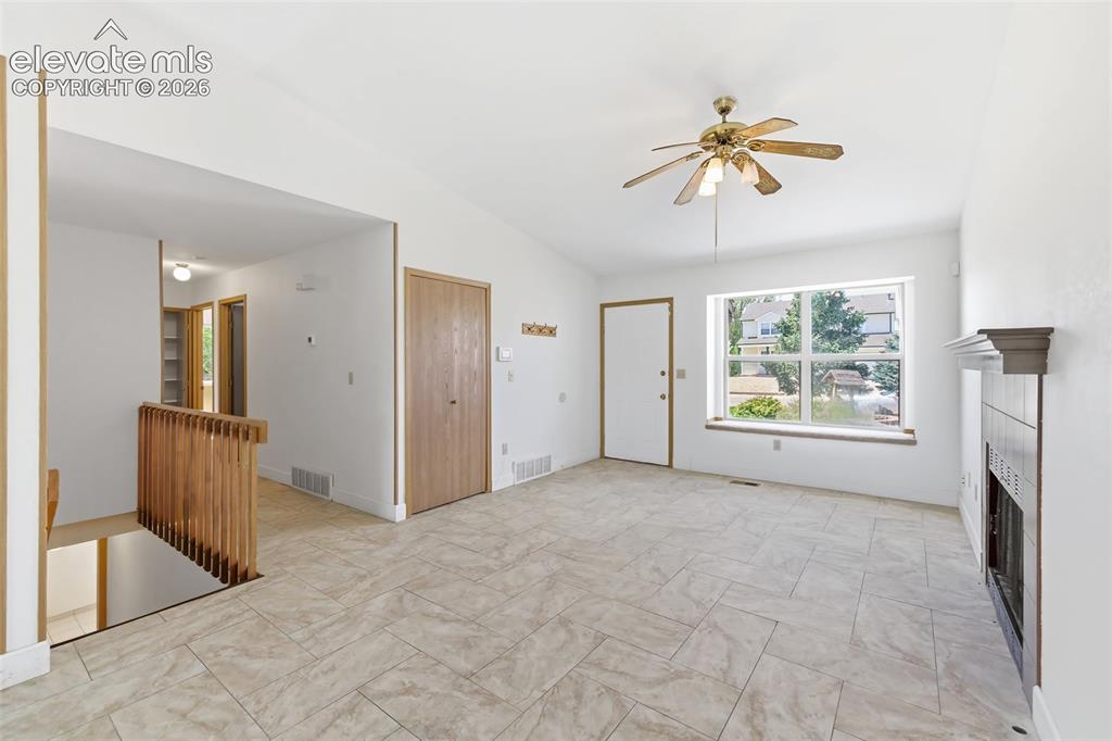 Image 16 of 29: Spacious living area featuring vaulted ceilings, a fireplace with a mantel,