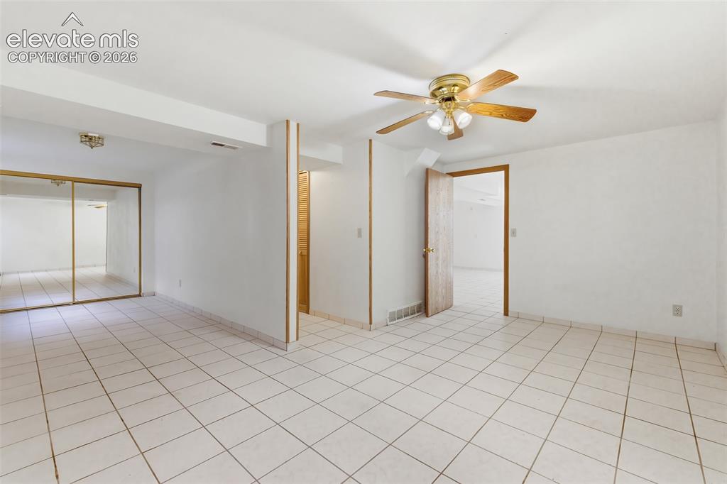 Image 18 of 29: Spacious interior featuring white tile flooring, white walls, a ceiling fan