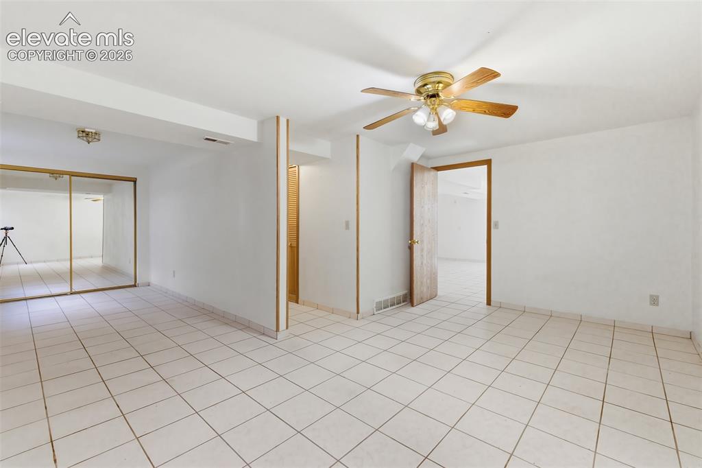 Image 19 of 29: Room featuring white tile flooring, white walls, and a ceiling fan with lig
