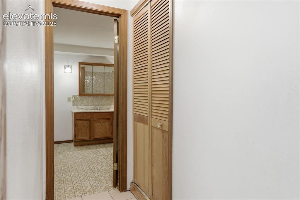 Image 20 of 29: Bathroom with wood-finish vanity, patterned backsplash, and wall-mounted li