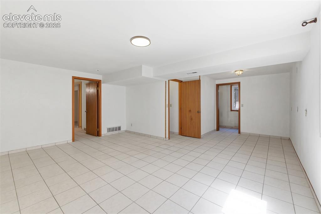 Image 23 of 29: Spacious interior room featuring light-colored tile flooring, white walls, 