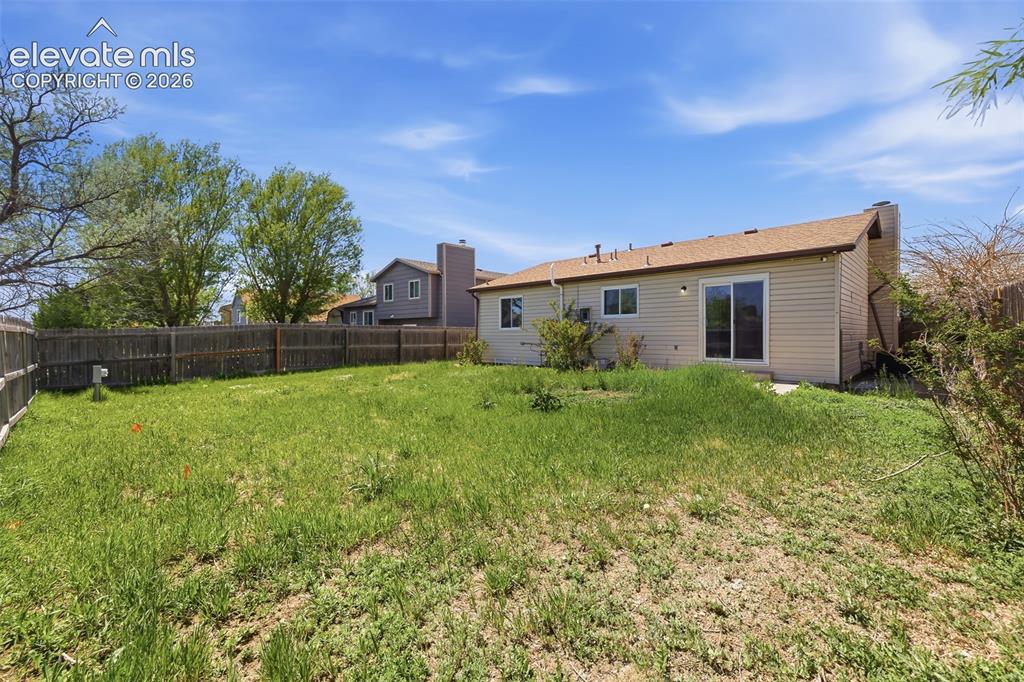 Image 26 of 29: Expansive backyard with a full wood privacy fence and a rear patio featurin