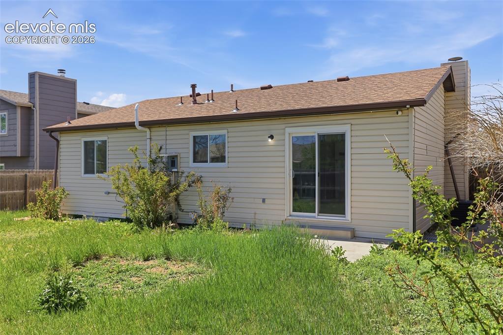 Image 27 of 29: Rear exterior of the residence featuring light-colored siding and a brown s