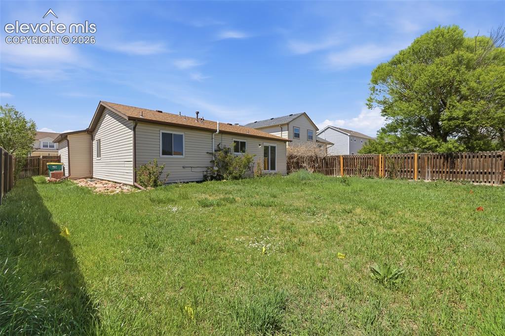 Image 29 of 29: Expansive backyard featuring a large grassy area, a privacy fence, and matu