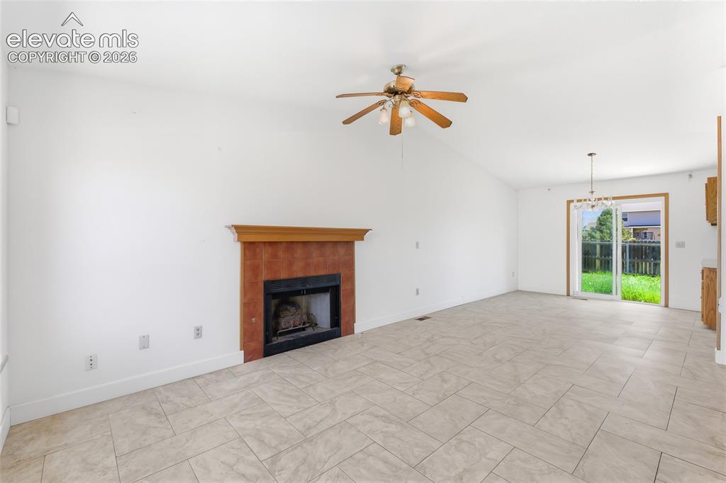 Image 3 of 29: Spacious living area featuring a central fireplace with a rich red tile sur