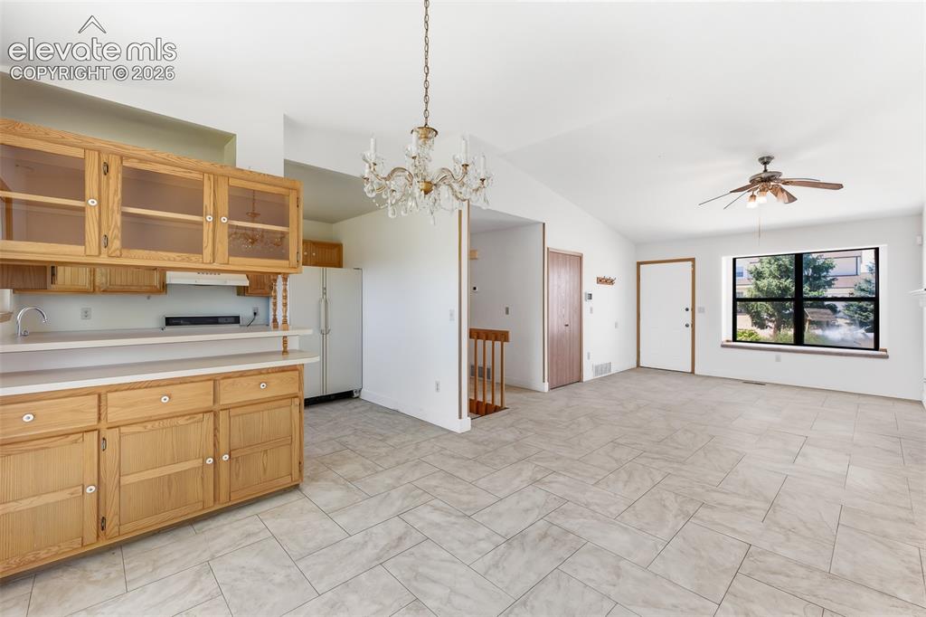 Image 7 of 29: Kitchen and living area featuring a vaulted ceiling with a crystal chandeli