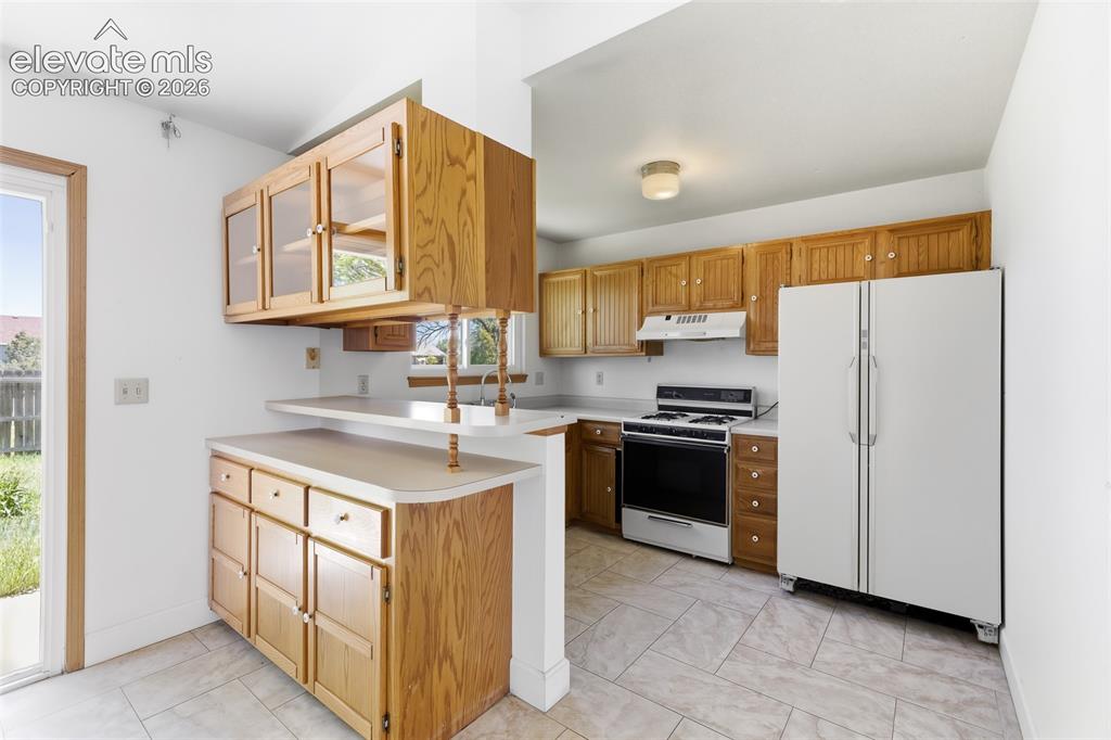 Image 9 of 29: Kitchen featuring wood cabinetry, light countertops, and tile flooring