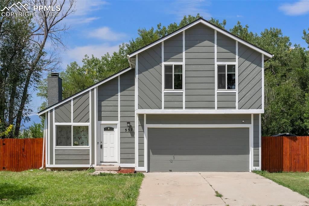 Caption: View of front of home featuring a garage, concrete driveway, and a chimney