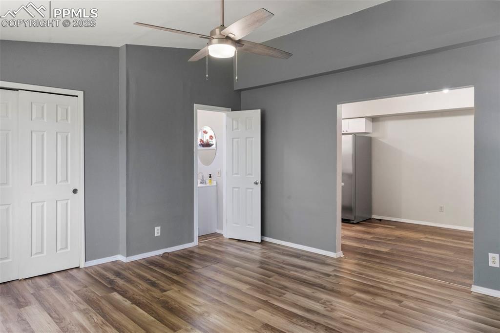 Image 10 of 24: Unfurnished bedroom with freestanding refrigerator, wood finished floors, a