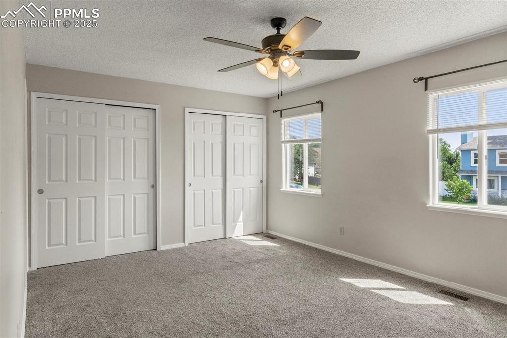 Image 13 of 24: Unfurnished bedroom featuring two closets, carpet floors, a textured ceilin