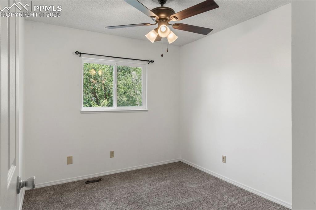 Image 17 of 24: Carpeted empty room featuring a textured ceiling and ceiling fan