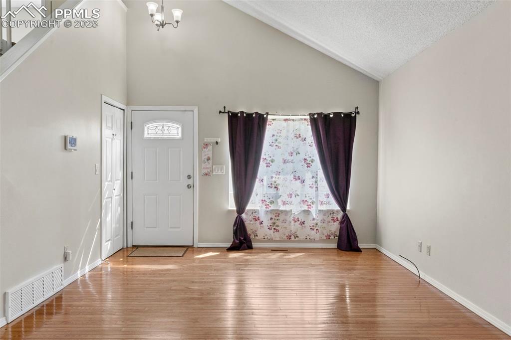 Image 2 of 24: Foyer featuring wood-type flooring, a chandelier, high vaulted ceiling, and