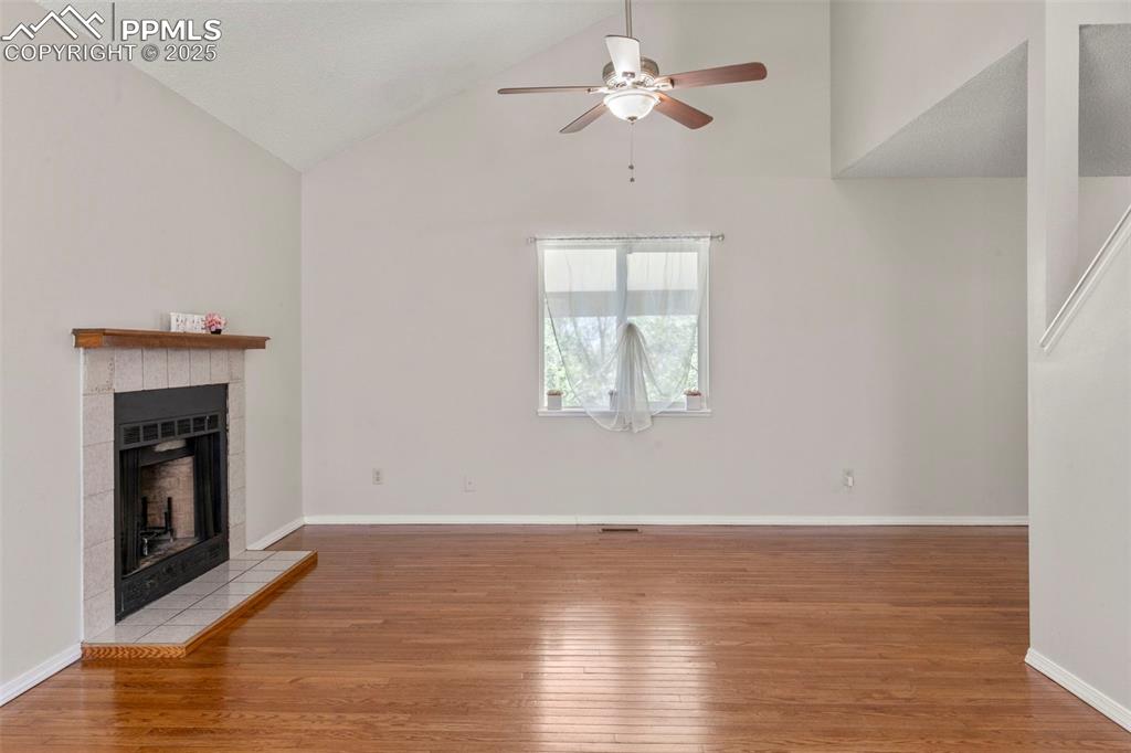 Image 3 of 24: Unfurnished living room with hardwood / wood-style flooring, a tiled firepl