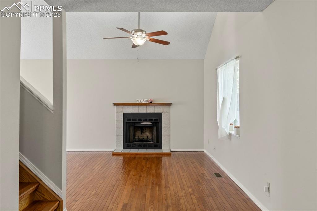 Image 4 of 24: Unfurnished living room featuring vaulted ceiling, hardwood / wood-style fl