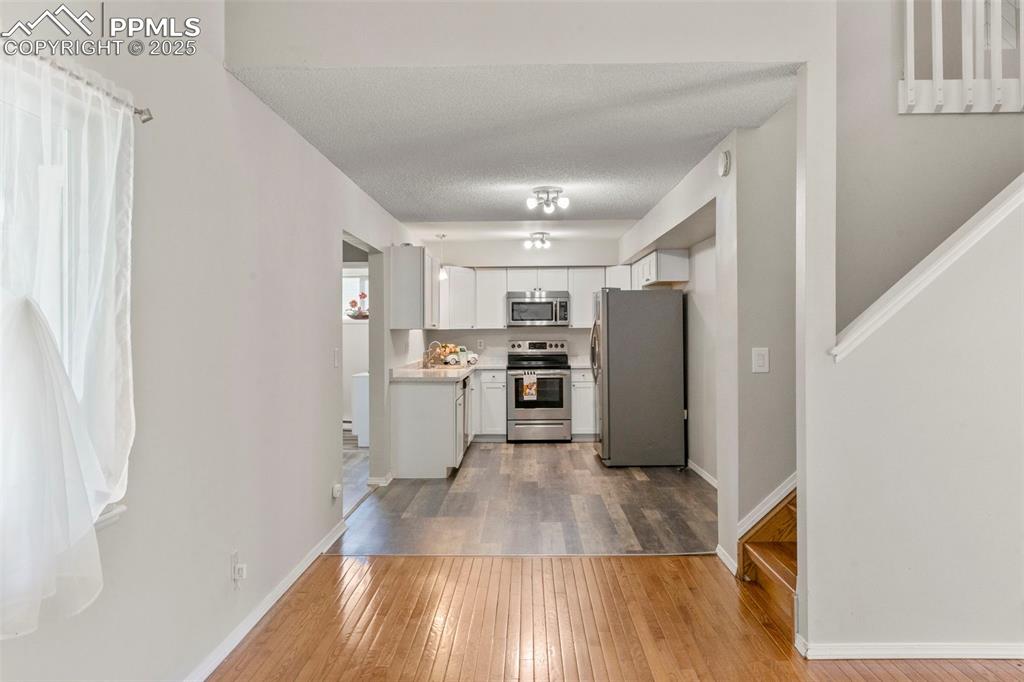 Image 5 of 24: Kitchen with light wood-style floors, stainless steel appliances, light cou