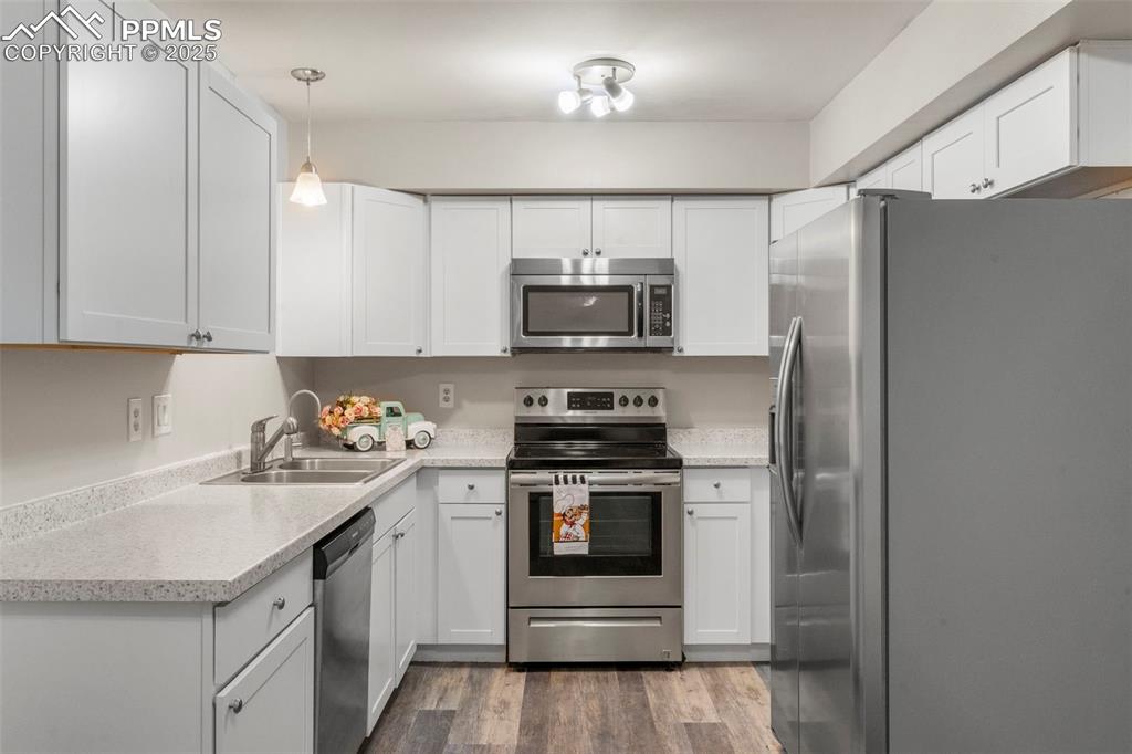 Image 6 of 24: Kitchen with appliances with stainless steel finishes, dark wood-style floo