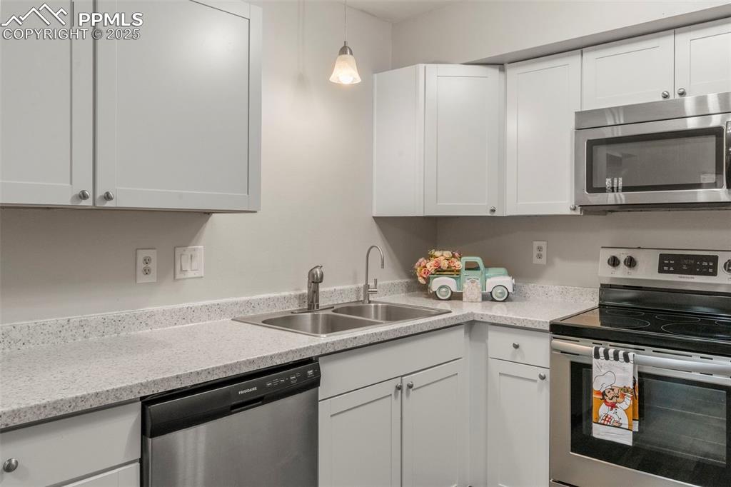 Image 7 of 24: Kitchen featuring stainless steel appliances, white cabinets, and decorativ