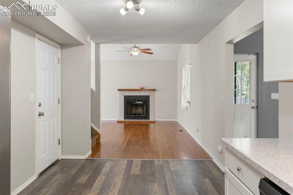 Image 8 of 24: Unfurnished living room featuring dark wood-style floors, a tiled fireplace