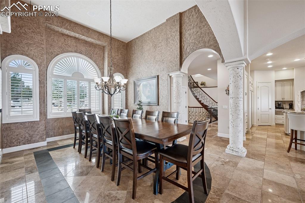 Image 12 of 50: Dining area with arched walkways, decorative columns, baseboards, a towerin
