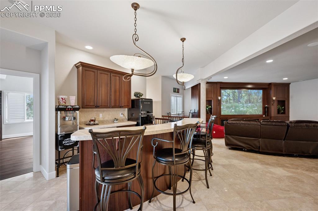 Image 36 of 50: Kitchen featuring a breakfast bar area, recessed lighting, tasteful backspl